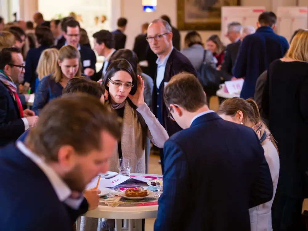 Participants working at standing tables in the World Café
