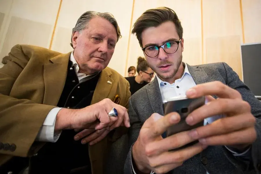 Two leaders of different generations looking at a screen together